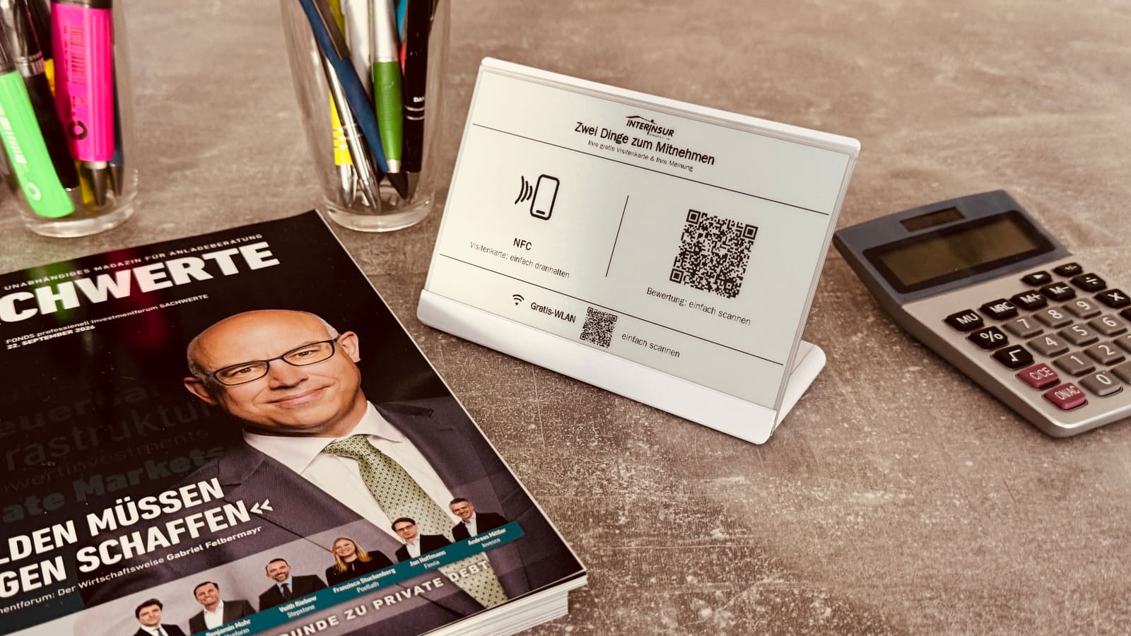 Landingdisplay am Empfang der InterInsur AG: Aufsteller mit 'Zwei Dinge zum Mitnehmen' neben Fachmagazin und Taschenrechner